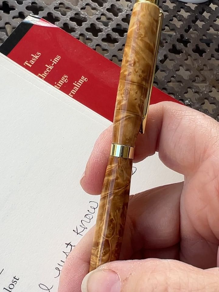 Burl wood pen with gold hardware over a journal page